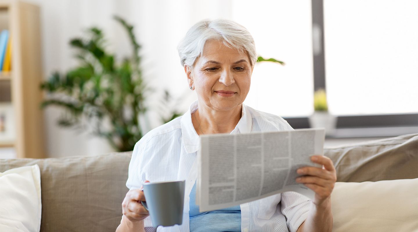Women drinking coffee holding a newspaper
